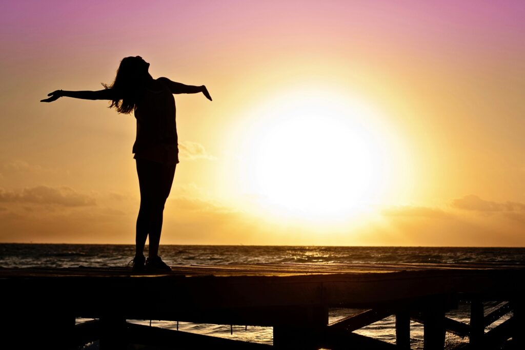 “Silhouette of a woman embracing the sunrise at the beach — symbolizing freedom, hope, and liberation from the pressure of the education system.”