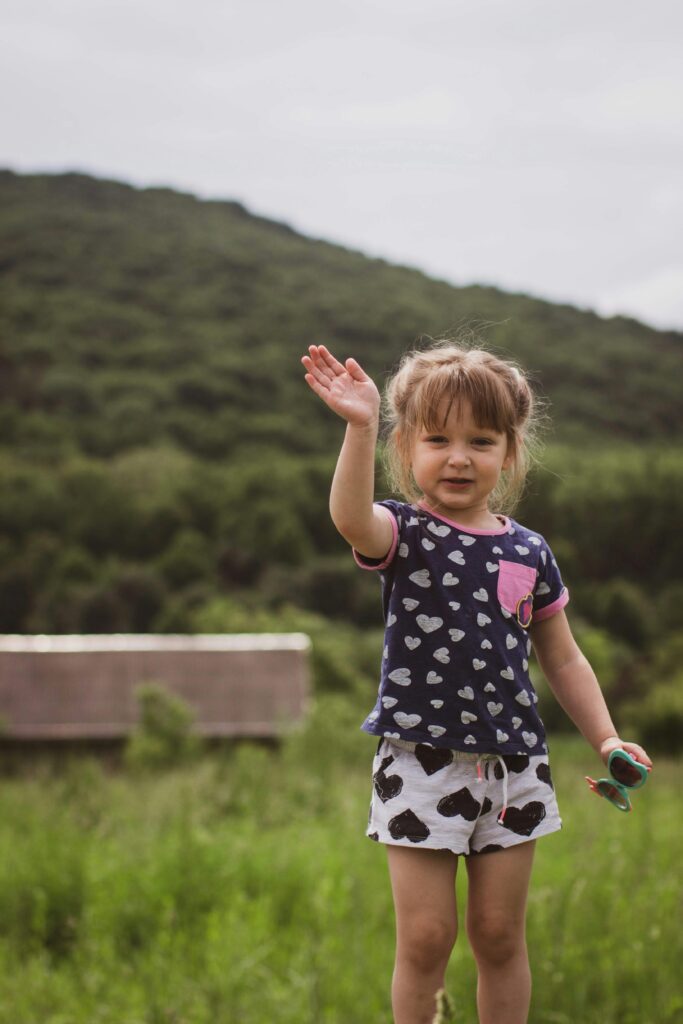 A smiling child waving, showing how kindness inspires others through small gestures.