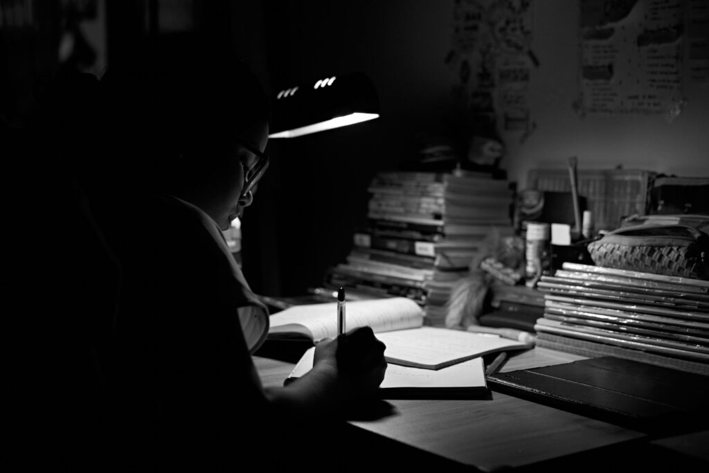 Student studying alone late at night under a lamp, showing the effort behind success and why we must applaud the journey.