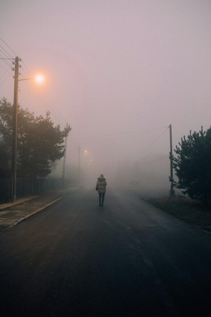 Person walking alone on an empty foggy road, symbolizing the unseen struggles and why we must applaud the journey.