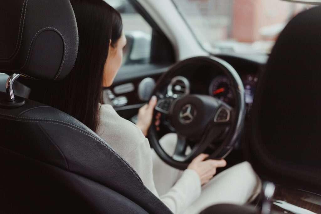 Woman learning to drive with support, breaking the “women can’t drive” stereotype through real practice and guidance.

