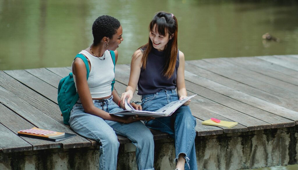 Two friends sitting together studying and supporting each other, showing why we should applaud the journey.
