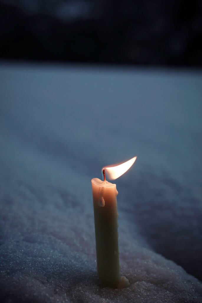 Candle burning in darkness symbolizing hope against the glorification of negativity in society.